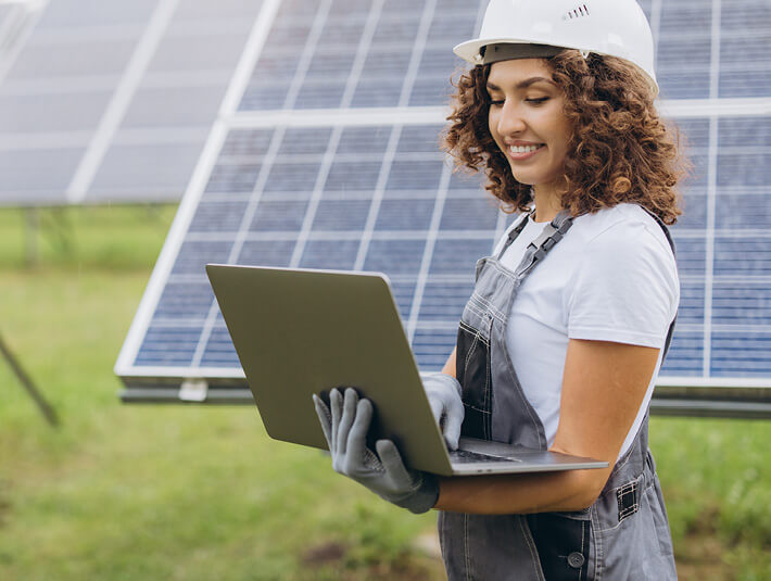 a woman in a construction helmet holds a laptop